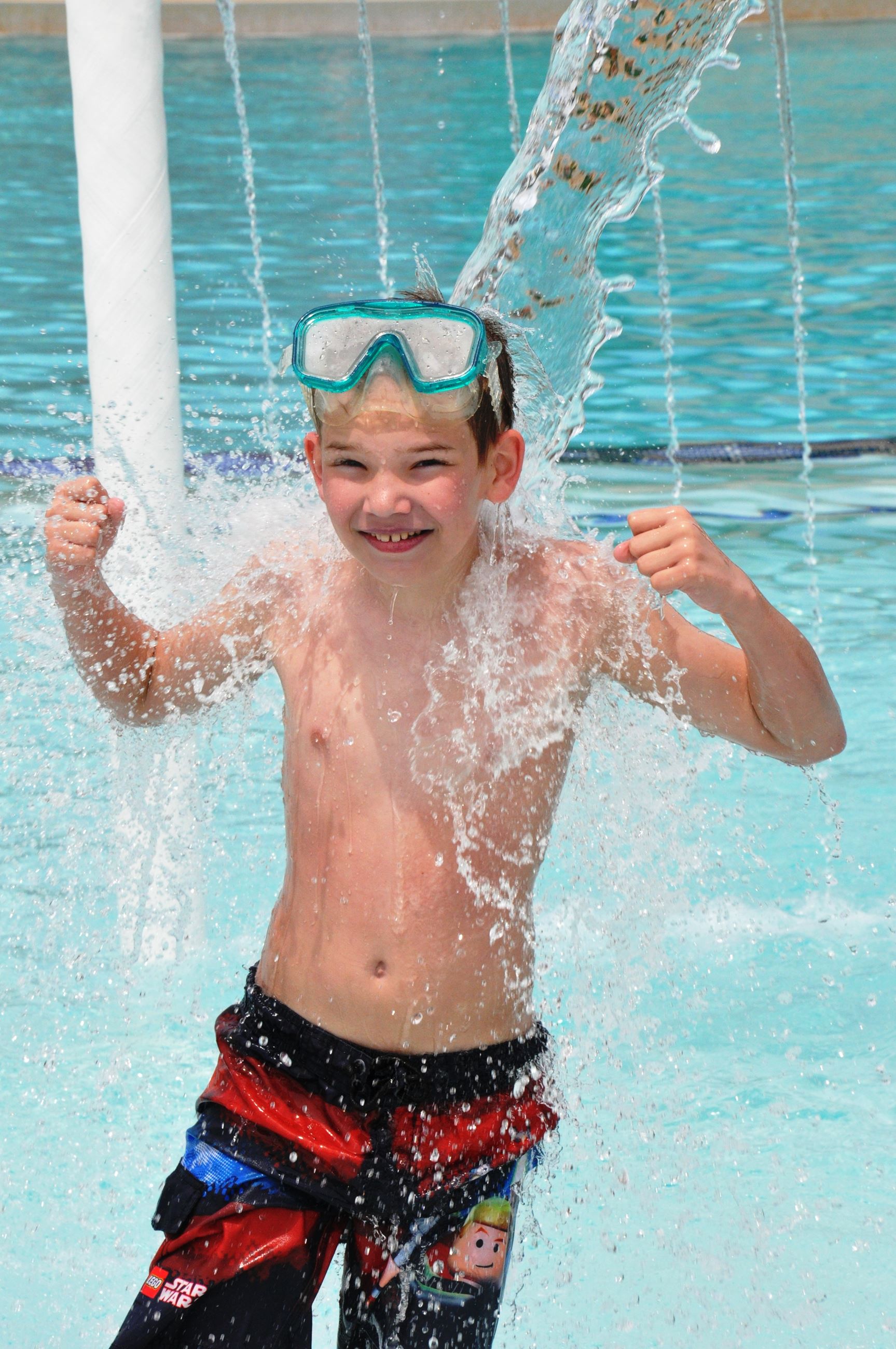 Boy having fun in a pool under a water feature.