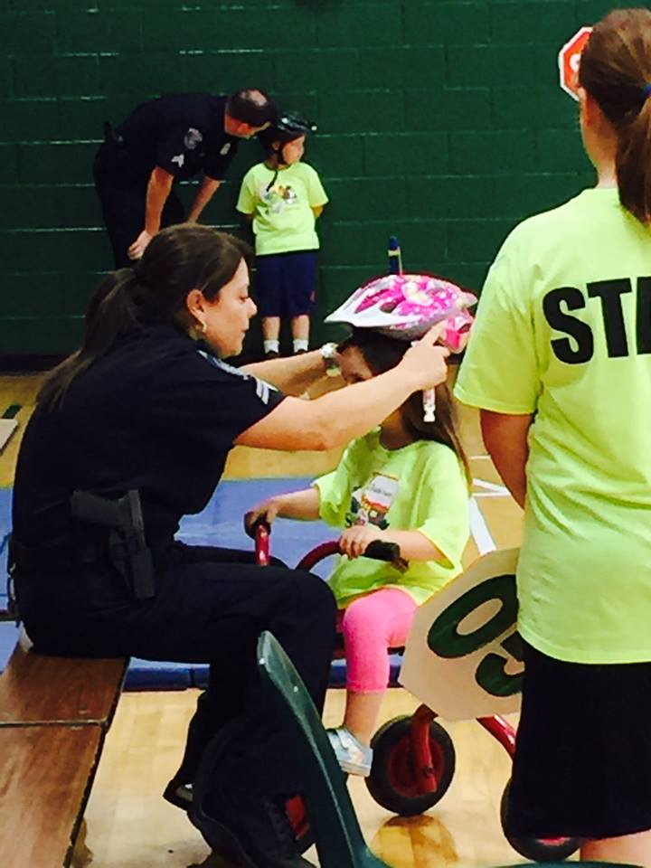 Officer Putting a Helmet on a Young Child Riding a Bike